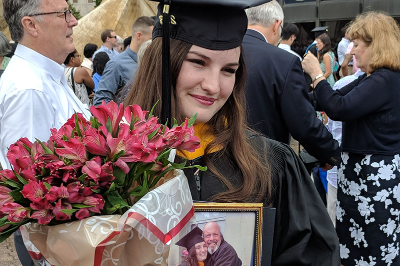 Ciara Jenkins on graduation day holding a photo of her dad. 