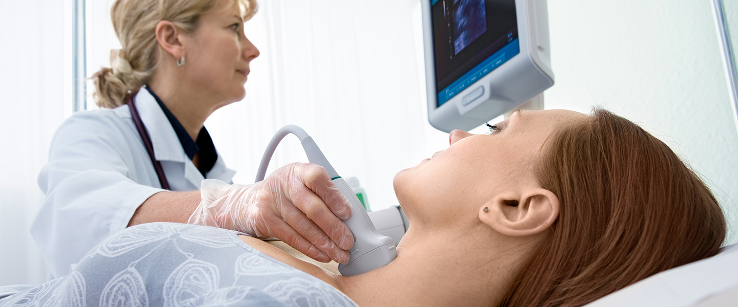 A doctor examines a woman's thyroid using ultrasound