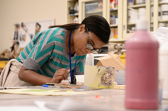 An Art Therapy students creates artwork in the classroom.