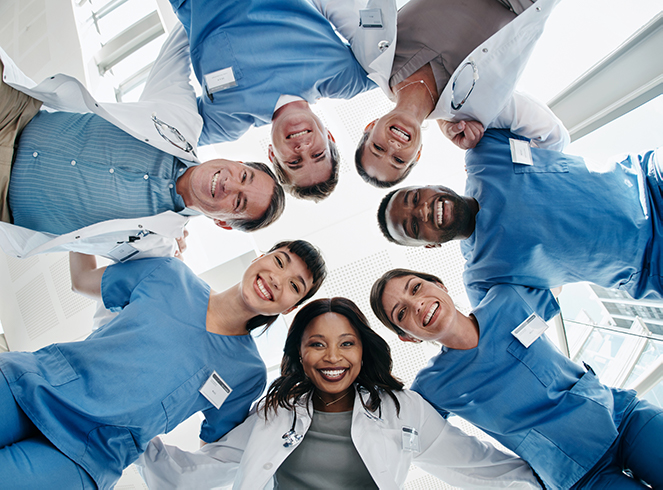 Health care workers standing in a circle with their arms around each other