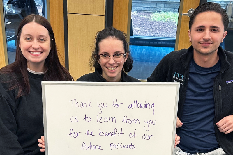 Three students with a dry erase board expressing gratitude for medical science donors