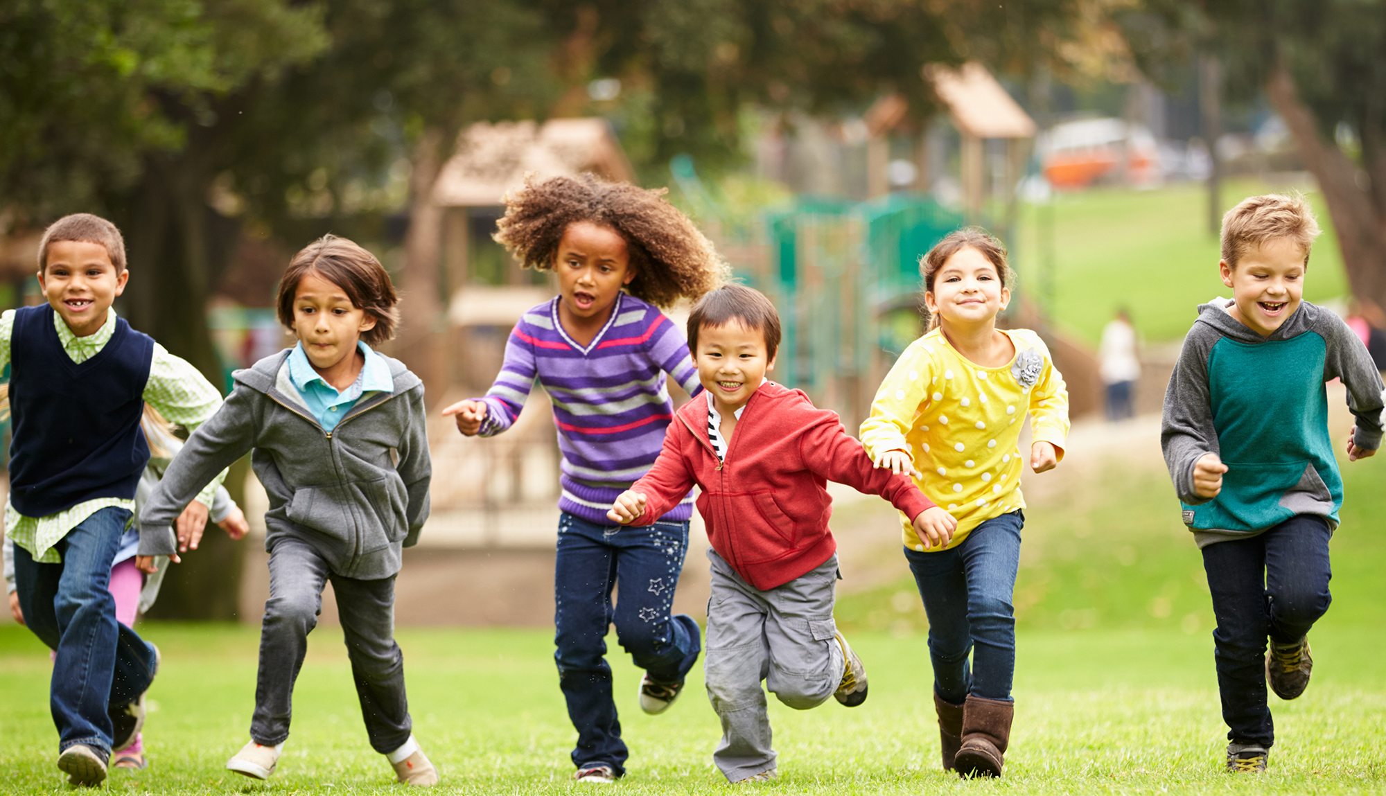 Several children run together in the park.