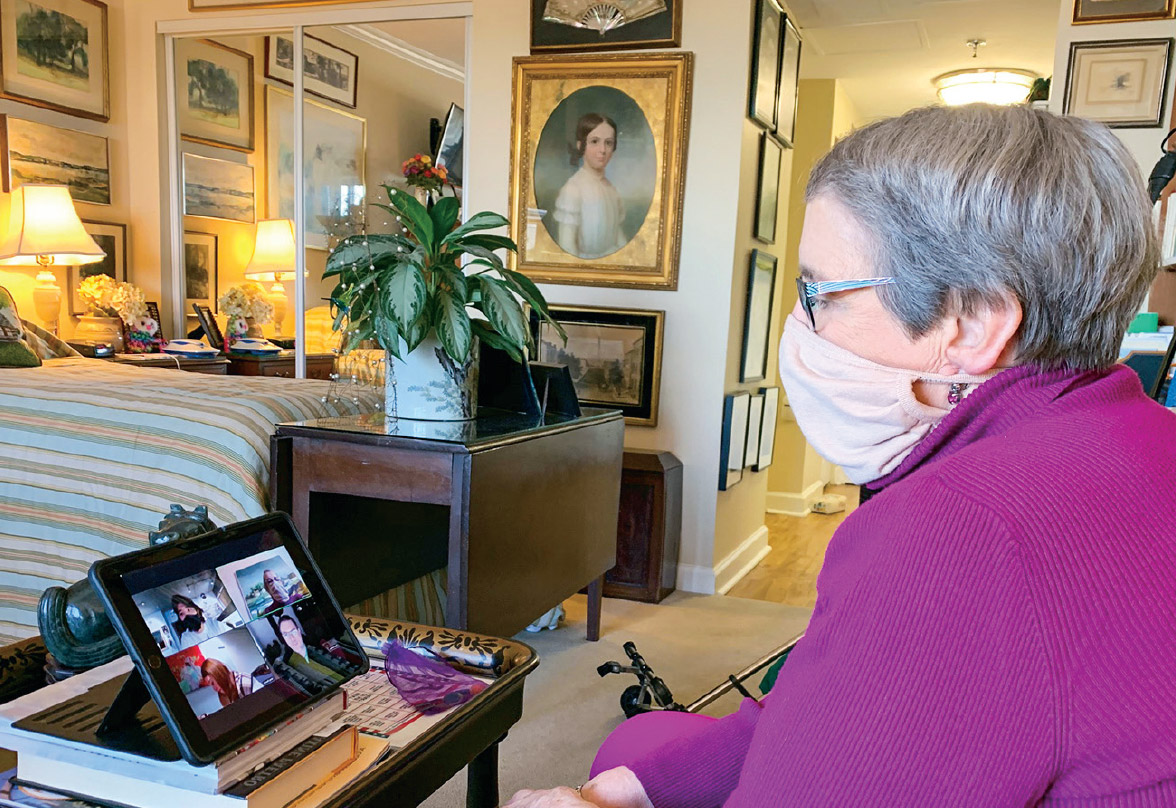 Emily Filer wears a mask while playing music bingo with students on her tablet in her home.