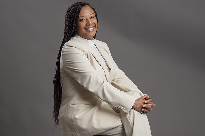 Image of Diane Holland in white suit sitting on a chair.