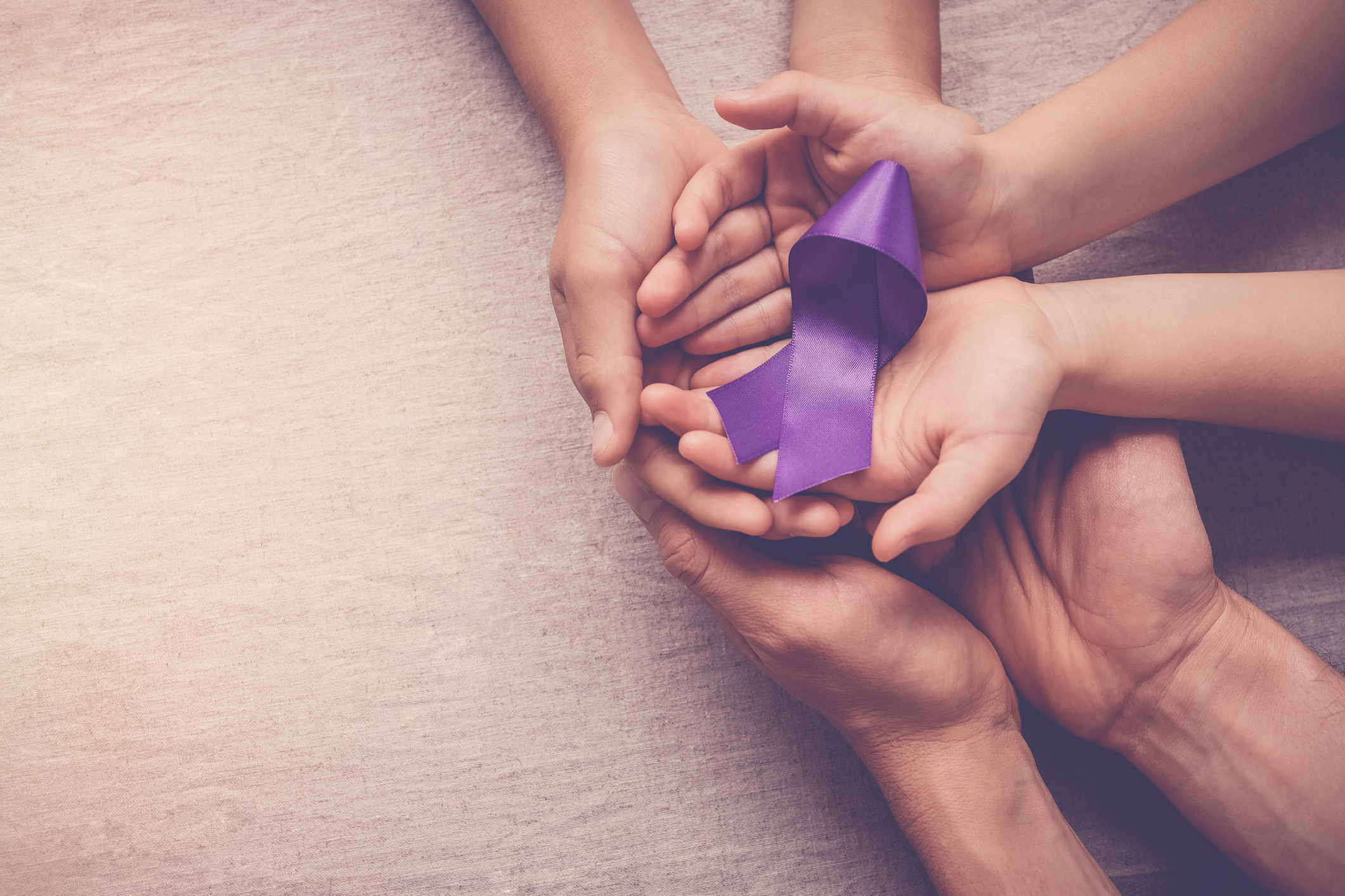 Hands holding a purple ribbon