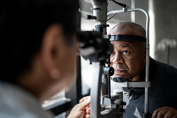 Male ophthalmologist uses a slit lamp to examine the eyes of an older gentleman.