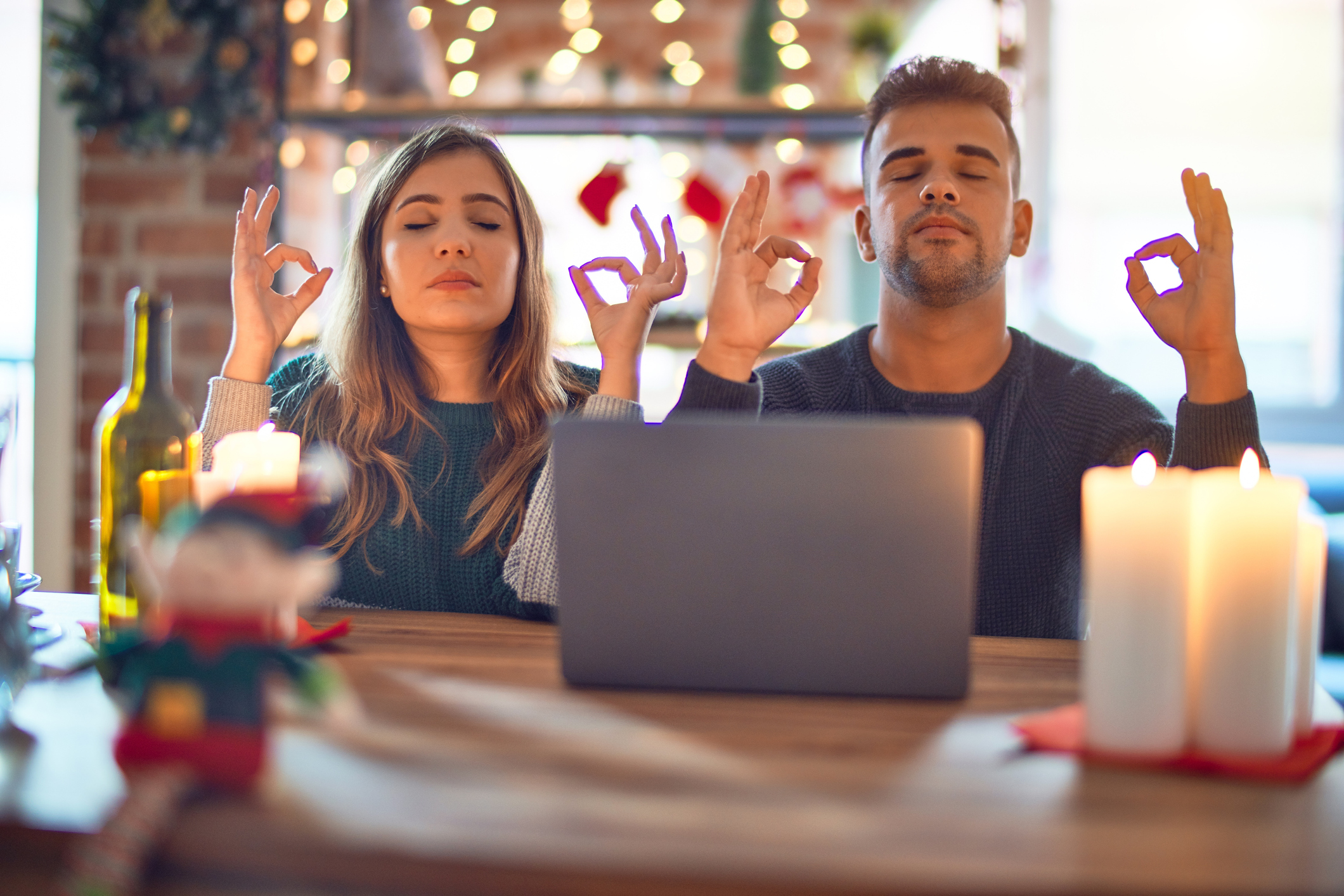 Man and woman meditating in front of an open laptop during the holidays