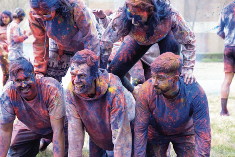 students covered in colored powder in a pyramid.