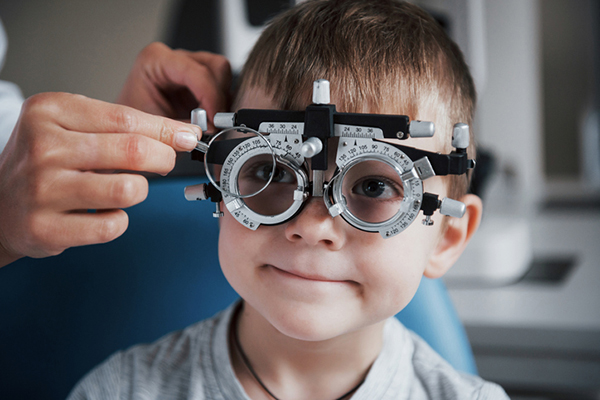 An ophthalmologist places adjustable optic lens frames on a child’s face
