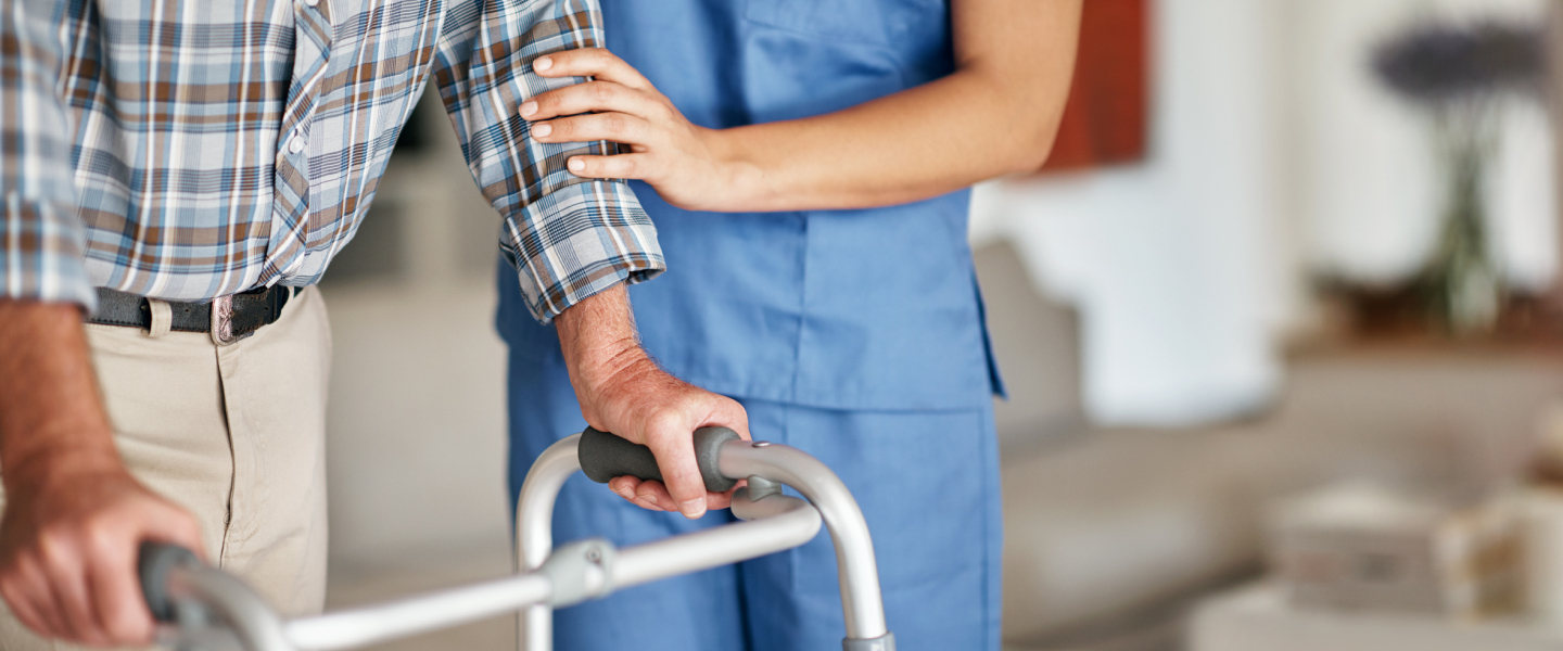 Nurse helping elderly patient use a walker
