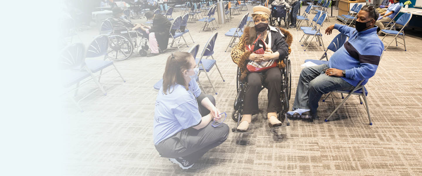 A medical professional speaking with two people at a public clinic