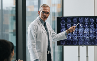 Doctor giving presentation at medical conference and pointing at x-ray images of a brain