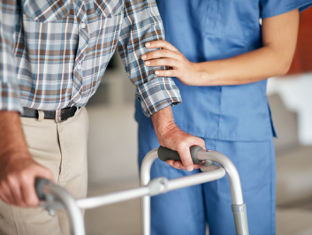 Nurse helping elderly patient use a walker