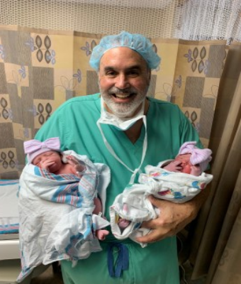Doctor DeLeon holding newborn twins