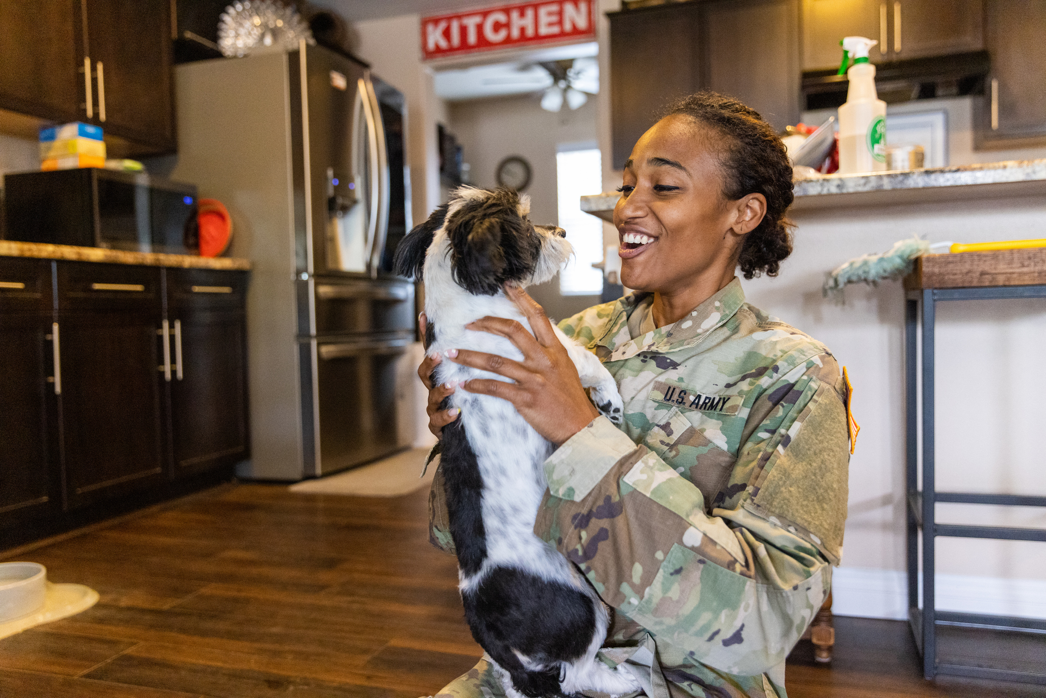 Image of female in uniform holding up a dog and smiling