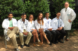 Musto and students seated on a bench in front of hedges