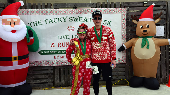 Runners in holiday attire smile for a photo at the Tacky Sweater 5k, a fun and festive event in Norfolk that raises funds for melanoma awareness and education. The organizer created the event in memory of her best friend, who lost her battle with melanoma cancer.