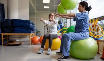 Therapist and femaie patient doing balance exercises sitting on rubber balls