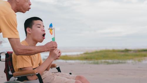 Child in wheelchair blowing on a pinwheel