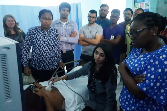 Fellows gather around a patient, one holding a stethoscope