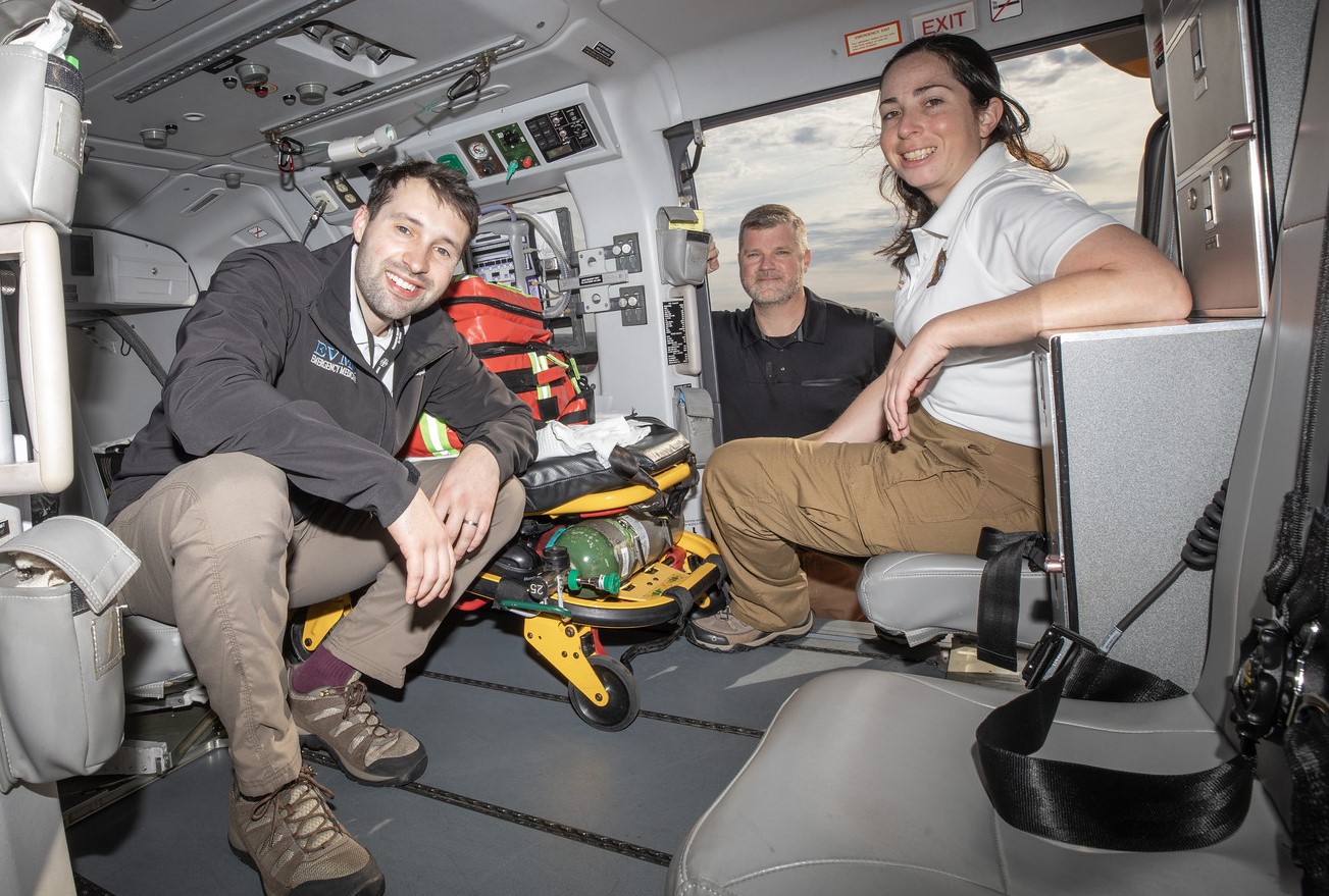 EMS residents inside a helicopter smile at the camera