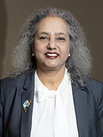 A professional woman with long silver gray curly hair smiles at the camera