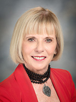 Woman with blonde hair wearing red jacket smiles at the camera