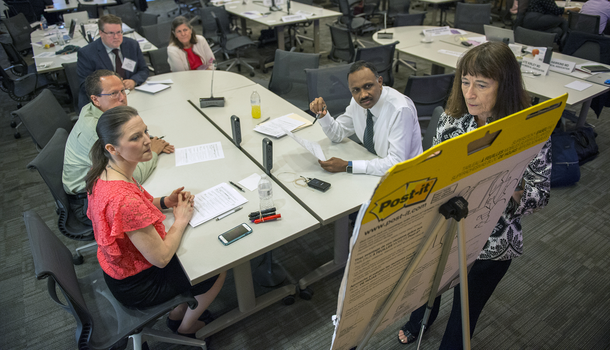 Several faculty members brainstorm on a large notepad in a small group session.