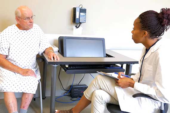 A resident talks with a Standardized Patient during a simulated patient experience.