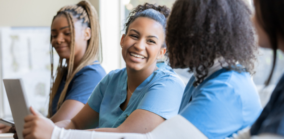Happy young adult nursing or medical student talks with classmate in university medical training class
