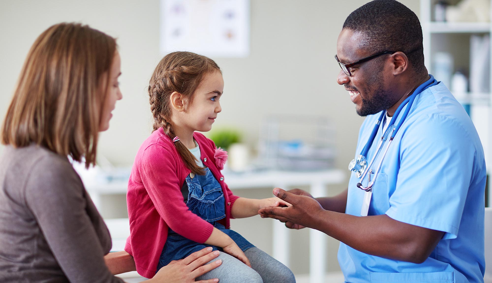 A physician assistant helps a young patient.