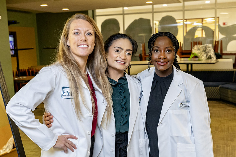 Three female students in white lab coats