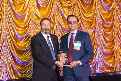 A photo of Dr. Alfred Abuhamad and Dr. Rehan Qayyum standing and holding a trophy. Dr. Abuhamad is presenting the award to Dr. Qayyum in honor of winning the Faculty Mentorship Award for 2023.