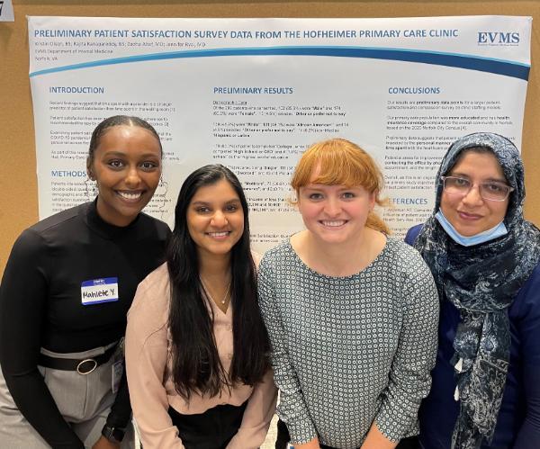 A group of EVMS researchers smile in front of their poster presentation.