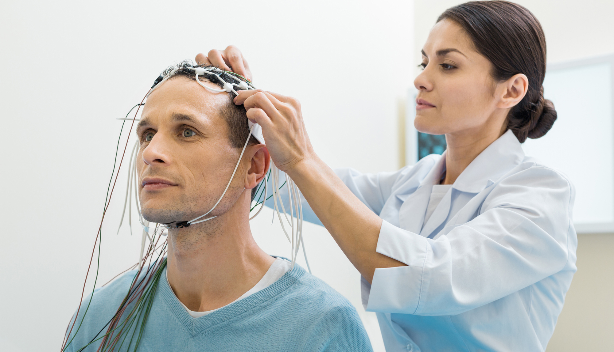 A doctor prepares a patient for an EEG test.