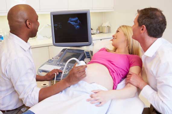 A physician performs an ultrasound on a pregnant patient.