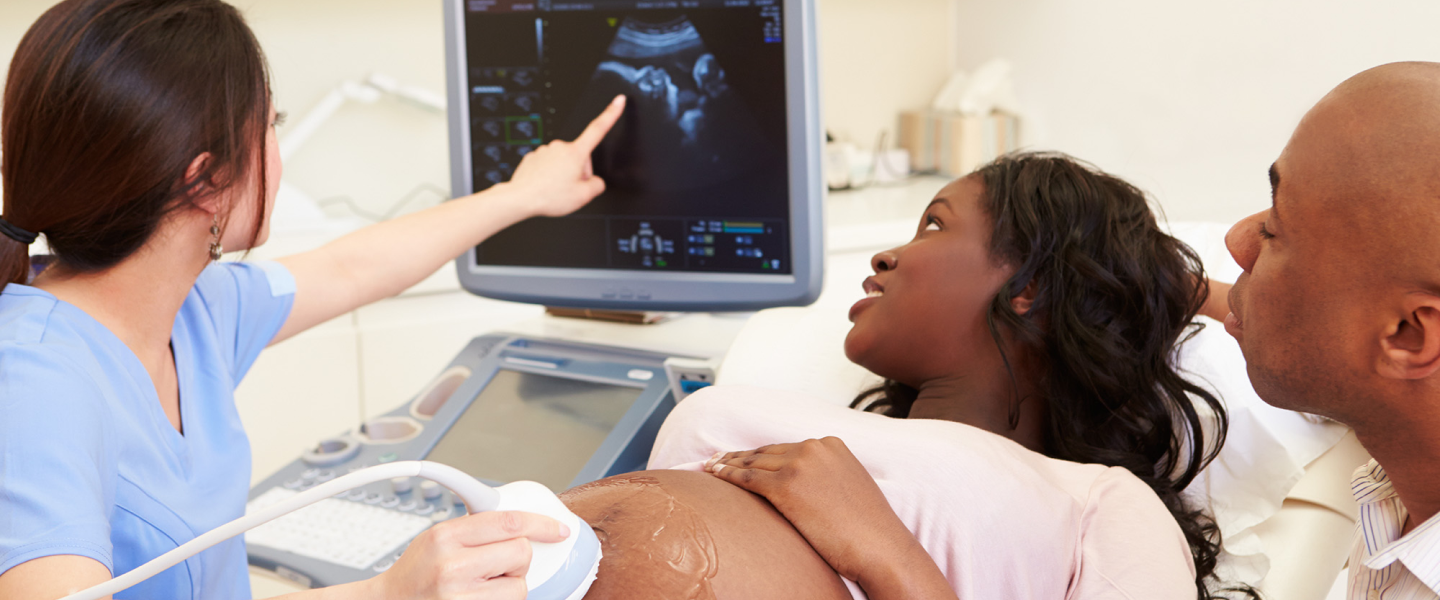 A man and woman look at ultrasound screen with doctor
