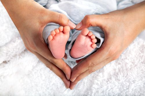 Hands forming a heart around two baby feet