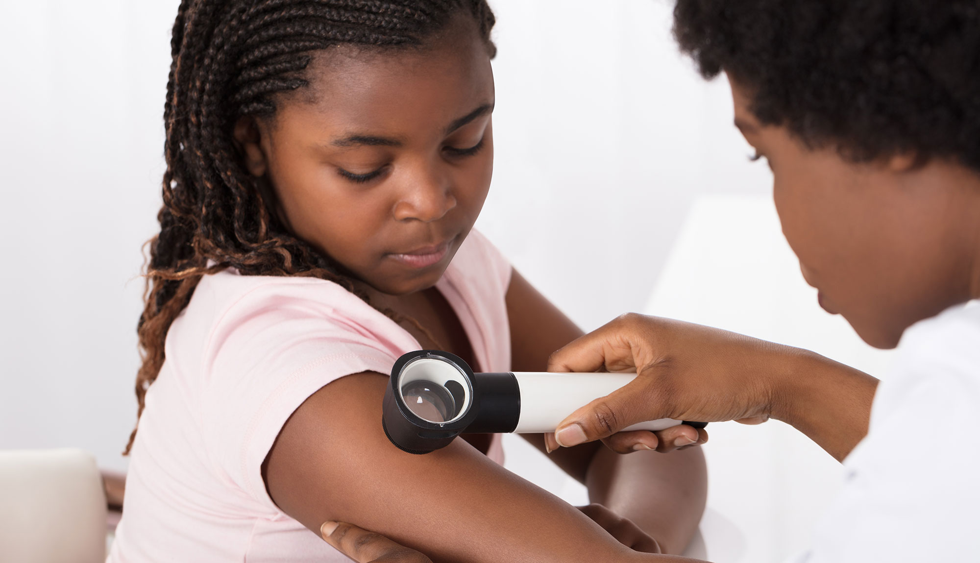 A physician looks at a vascular birthmark on a child's arm.