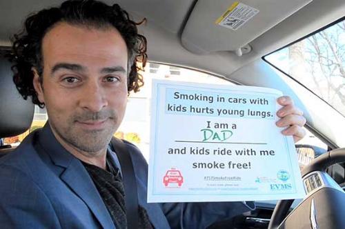 A parent holds a sign pledging to adhere to the 757 Smoke Free Ride campaign.