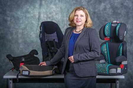 Dr. Kelli Will poses in front of booster seats.