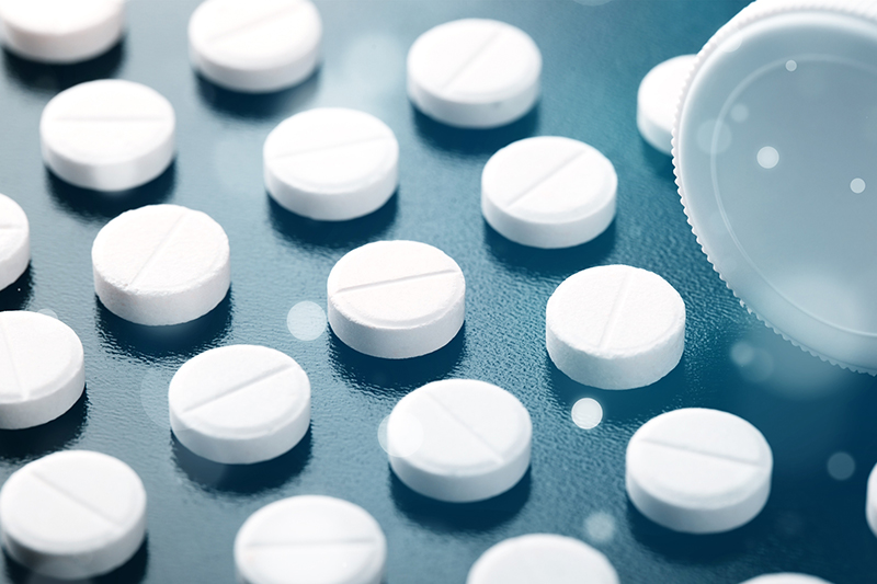 A close-up of white pills arranged in straight lines on a dark surface