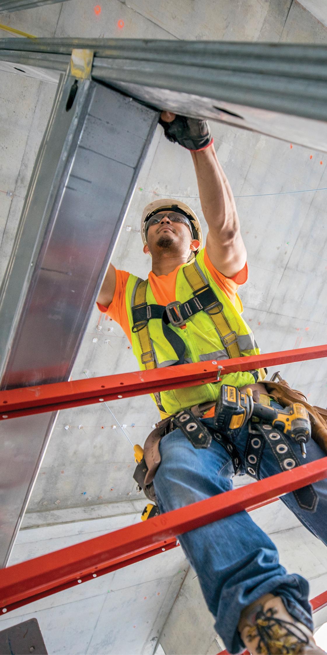 A worker installs framing in a first step to transform the concrete shell into offices and classrooms.