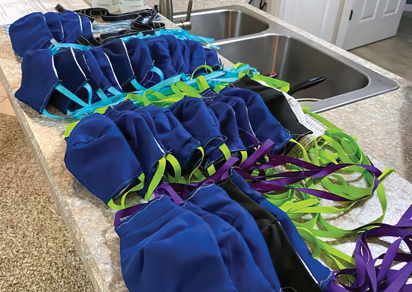 Dozens of hand-sewn face masks lined up on a counter for distribution.