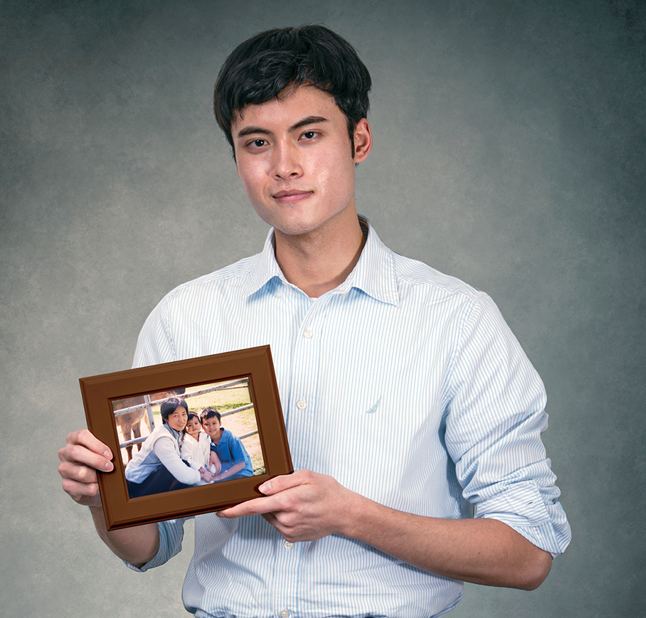 MD Class of 2024 student Jason Bard sits on a stool holding a framed photograph of his grandmother with him as a small child.