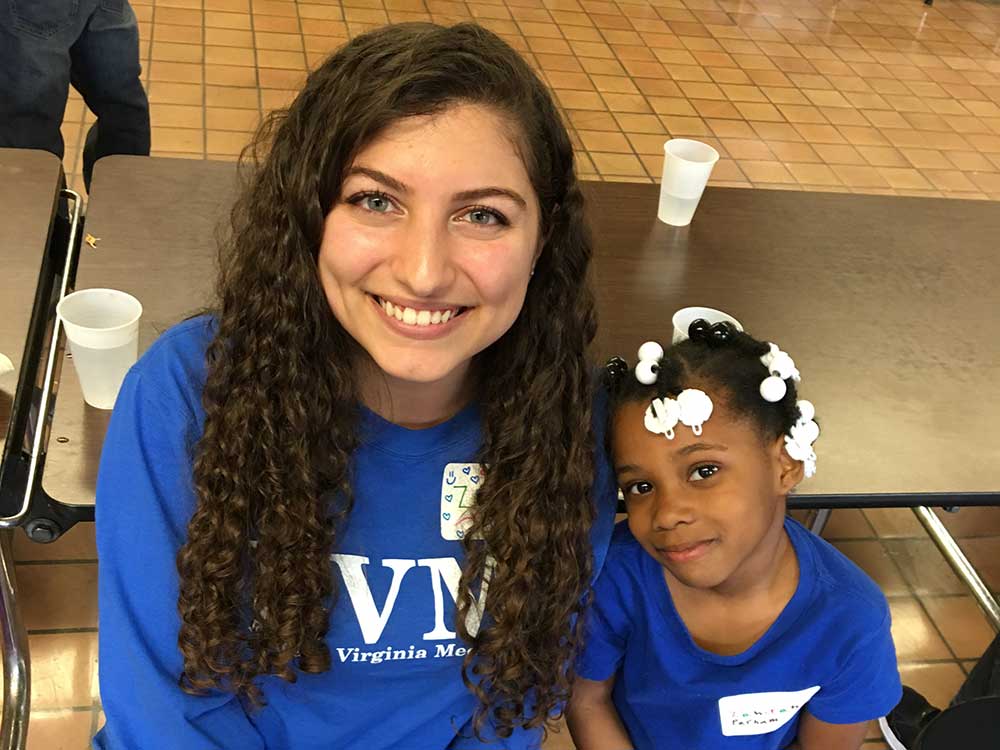 An EVMS volunteer poses with a Young at Heart club young member