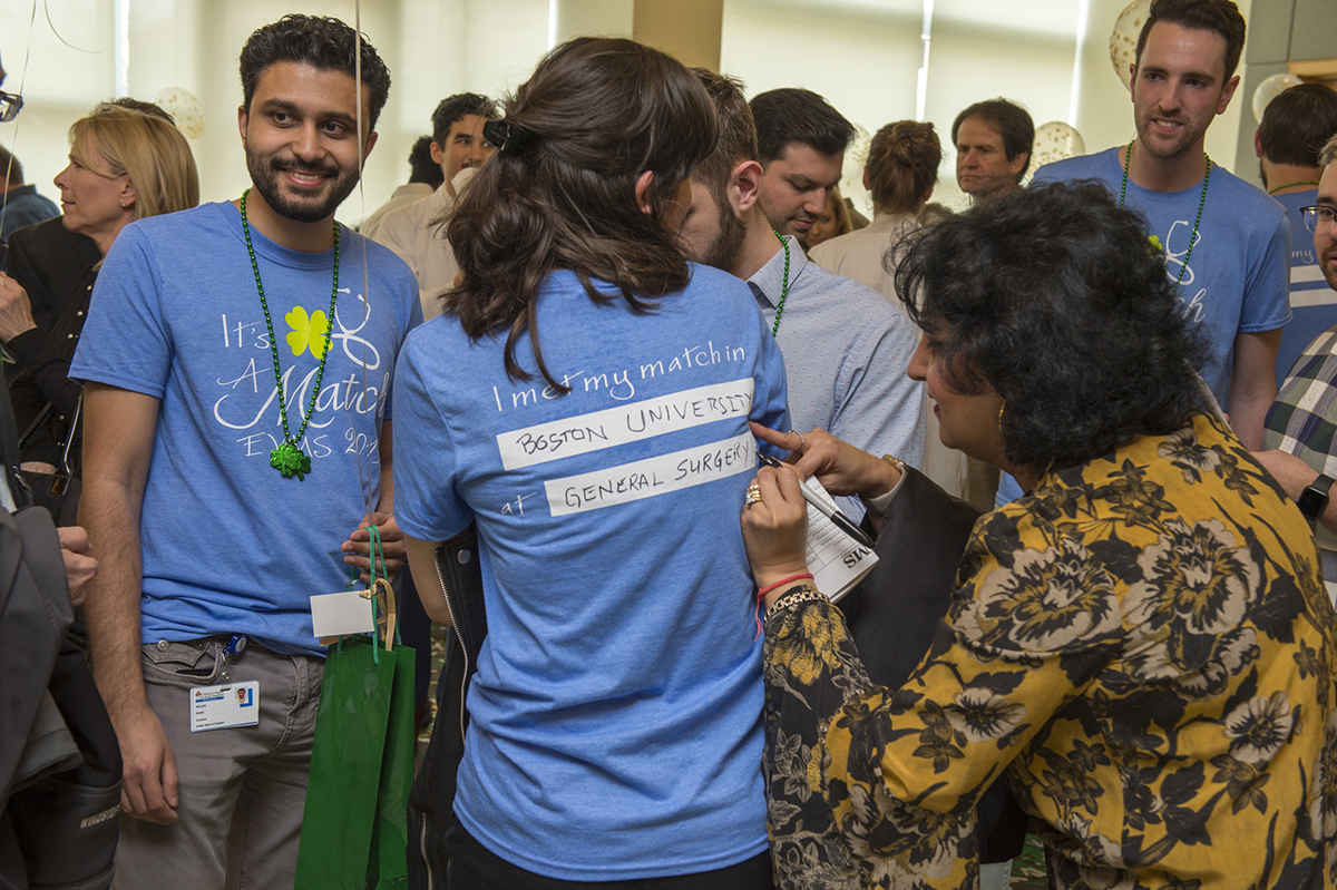 A mother reads the Match Day results from the back of her daughter's t-shirt.
