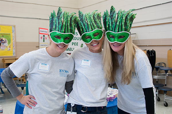 EVMS students wearing masks fashioned as asparagus to show it's impact on the body's functions.
