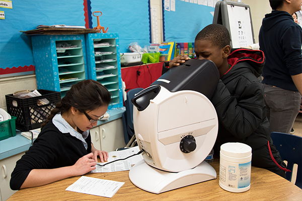 Elementary students using a machine to test their vision.