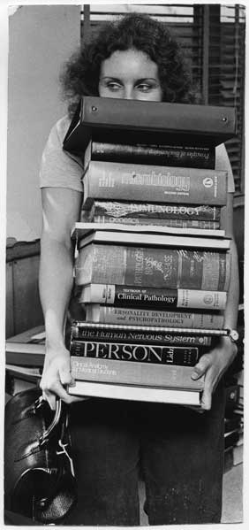 Linda Staiger holds a stack of books that goes as high as her nose.